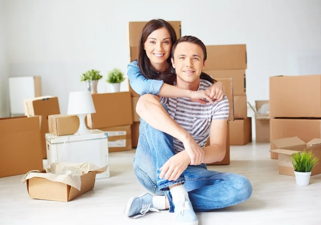 Jeune couple emménageant dans leur premiere maison avec cartons — rachat de credit immo et travaux